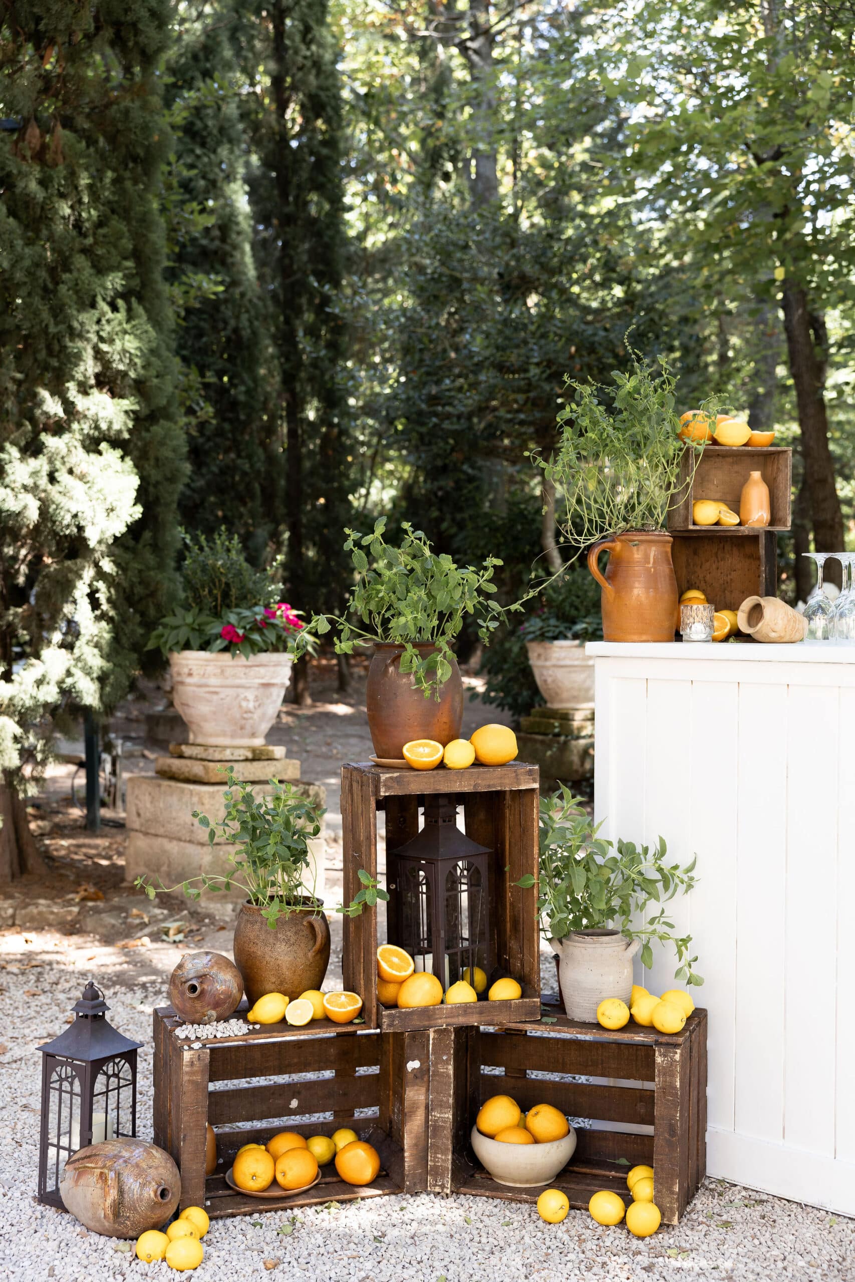 Décoration rustique de jardin pour un bar à limonade : caisses en bois, jarres en terre cuite, herbes fraîches, citrons et oranges.