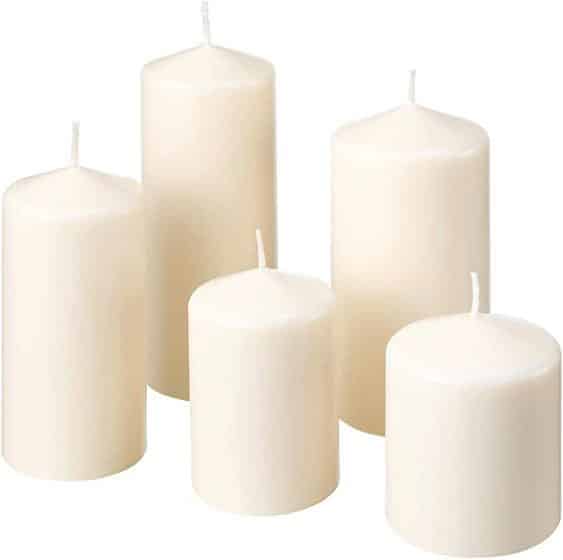 Lot de cinq bougies piliers cylindriques blanches ou crème, de hauteurs variées, sur fond uni.